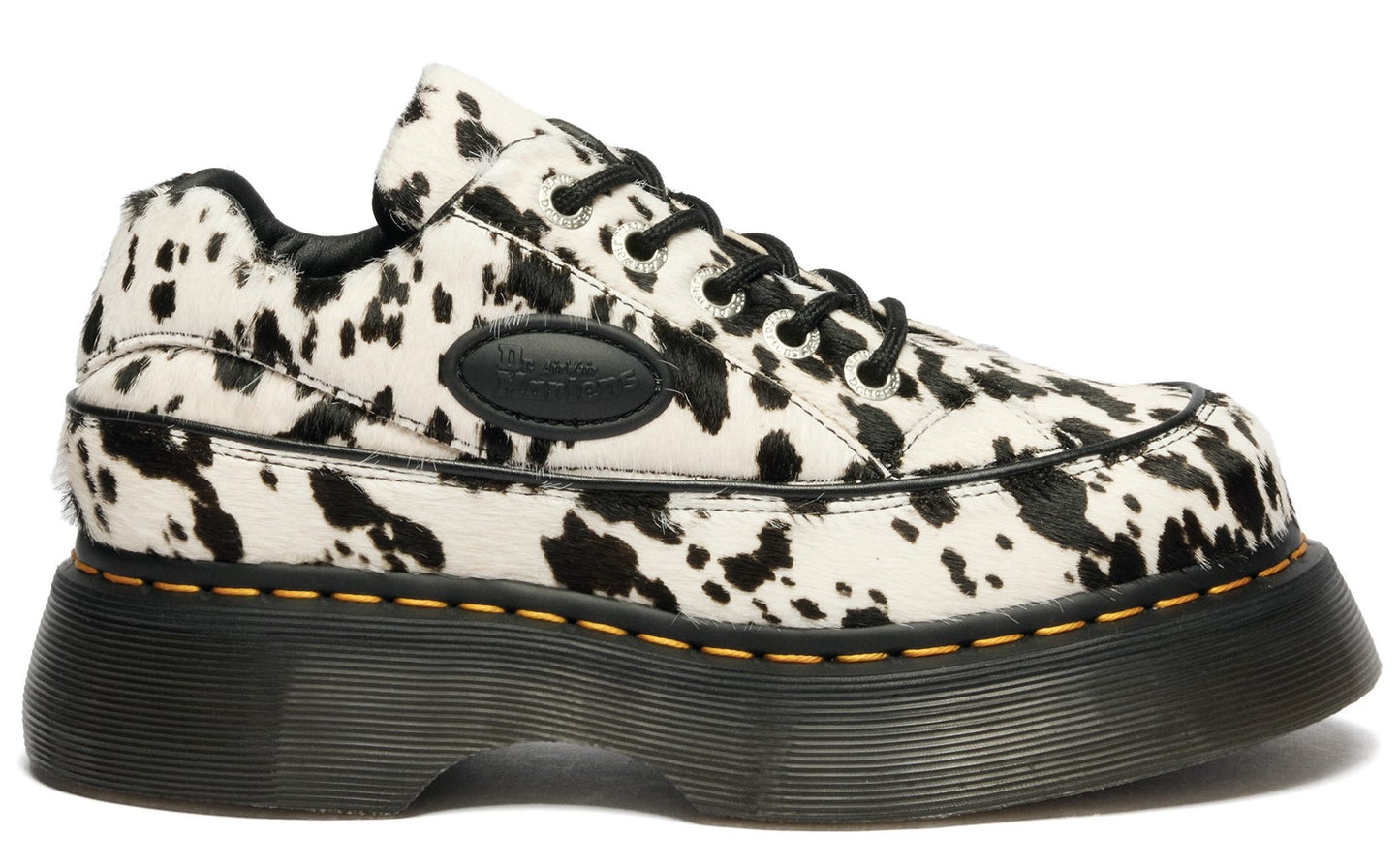 Low-top cow-print shoes with black laces and a thick, black sole.