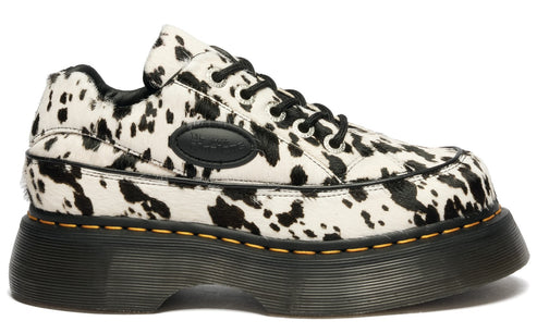 Low-top cow-print shoes with black laces and a thick, black sole.