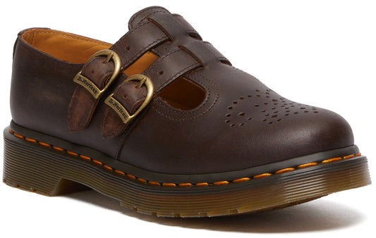 A dark brown leather T-strap shoe with two adjustable bronze-colored buckles, brogue-style perforations on the toe, and a signature thick air-cushioned sole with yellow welt stitching.