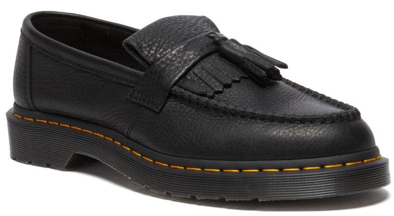 A black leather loafer with a pebbled texture, a kiltie fringe, and a tassel detail on the upper, featuring yellow stitching along the welt and a chunky rubber sole.