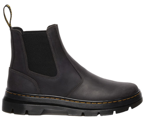 Side view of an ankle-high, dark gray, leather boot with elastic side panels and a yellow-stitched sole.