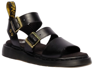 Black leather sandal with two straps, gold buckles, black soles, and a yellow label.