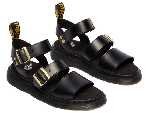 Pair of black platform sandals with two straps and gold buckles, and a yellow tab on the heel strap.
