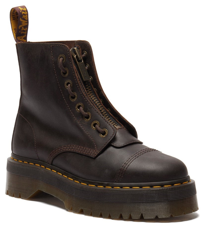 A dark brown leather platform combat boot with a front zipper, reinforced toe cap, yellow welt stitching, and a branded pull tab at the heel.