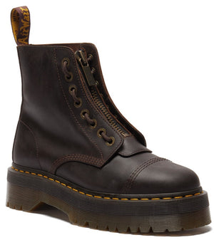 A dark brown leather platform combat boot with a front zipper, reinforced toe cap, yellow welt stitching, and a branded pull tab at the heel.