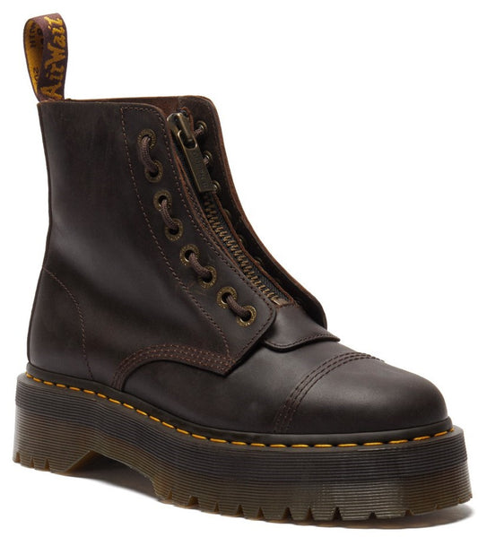 A dark brown leather platform combat boot with a front zipper, reinforced toe cap, yellow welt stitching, and a branded pull tab at the heel.