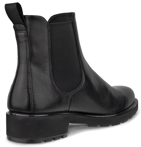 A black leather Chelsea boot shown from the side and back angle, featuring a pull tab at the collar, a side elastic gore panel, and a thick, chunky rubber lug sole.