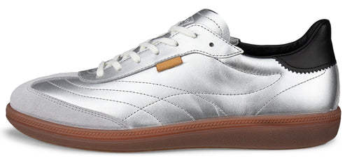 A silver sneaker with white laces and a brown sole.