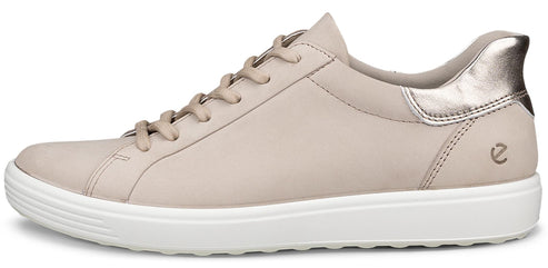 A low-top sneaker in beige leather with white rubber soles.