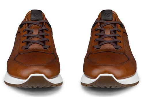 A pair of tan leather low-top sneakers with dark brown laces, brown leather tongues with a dark grey logo tab, and white midsoles with brown rubber outsoles, viewed from the front.