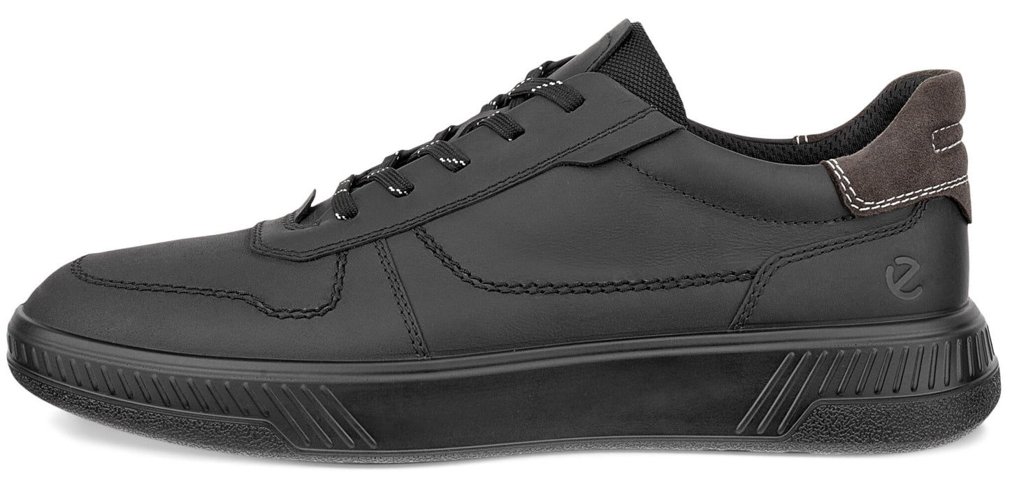 A low-top, black leather sneaker with matching laces, black rubber sole featuring a ribbed pattern on the front and back, and a grey suede accent on the heel tab.