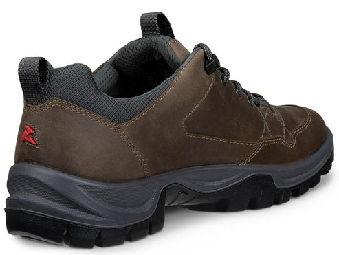 A brown leather low-top hiking shoe with a dark grey collar, thick black rubber sole with deep treads, and a small red logo on the heel tab.