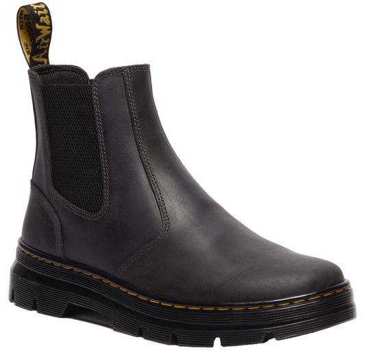 Black Chelsea boot with elastic side panels, yellow stitching and black lug sole.