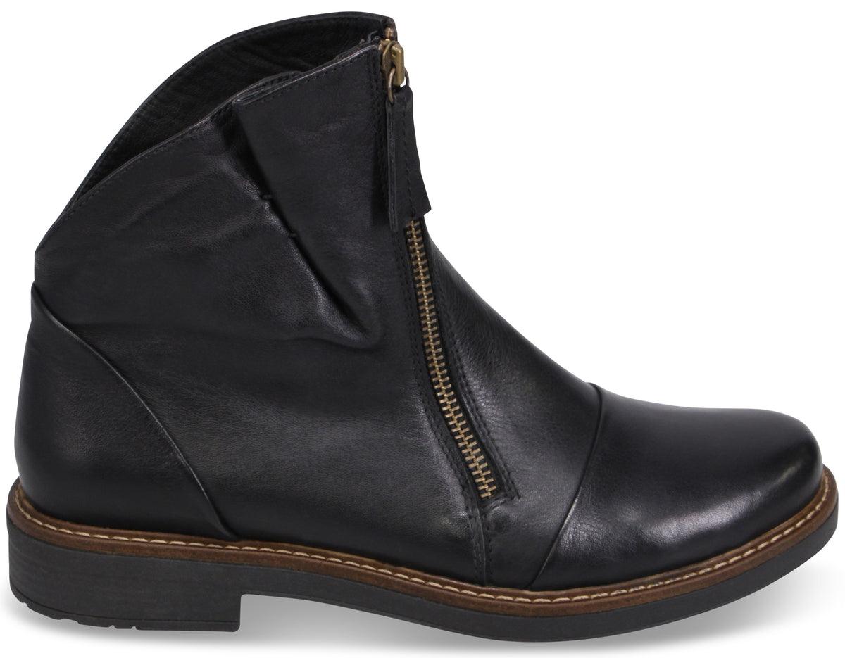 A black leather ankle boot with a slanted silhouette, a front-facing gold-tone zipper, and a dark, thick rubber sole with a visible stitched welt.