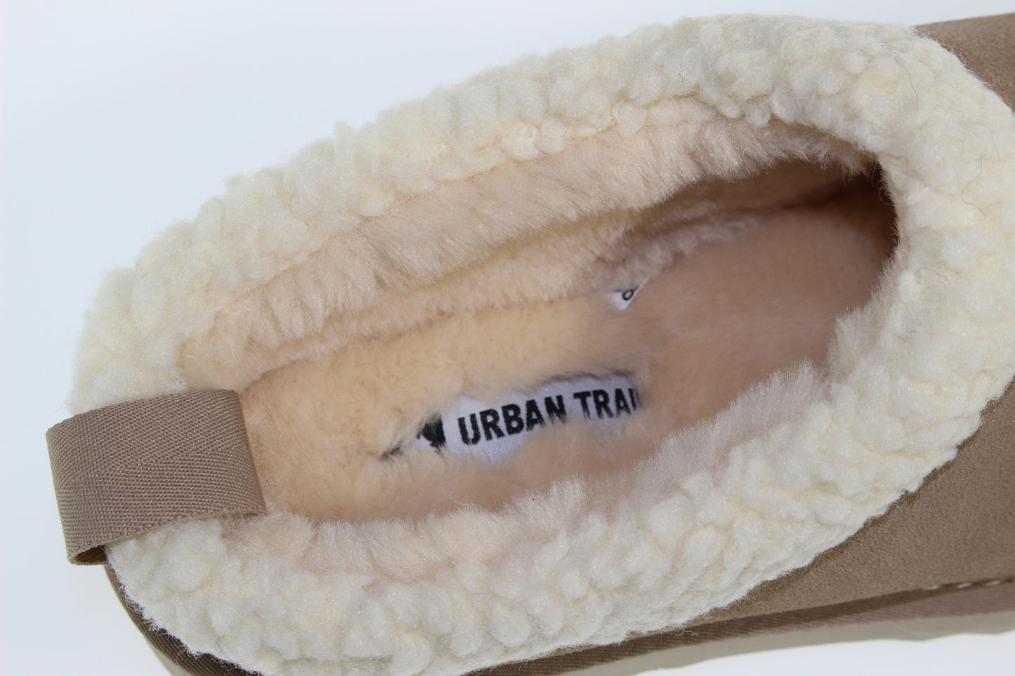 Close-up of the interior of a shoe, showing beige faux-fur lining with a label printed with "URBAN TRA".