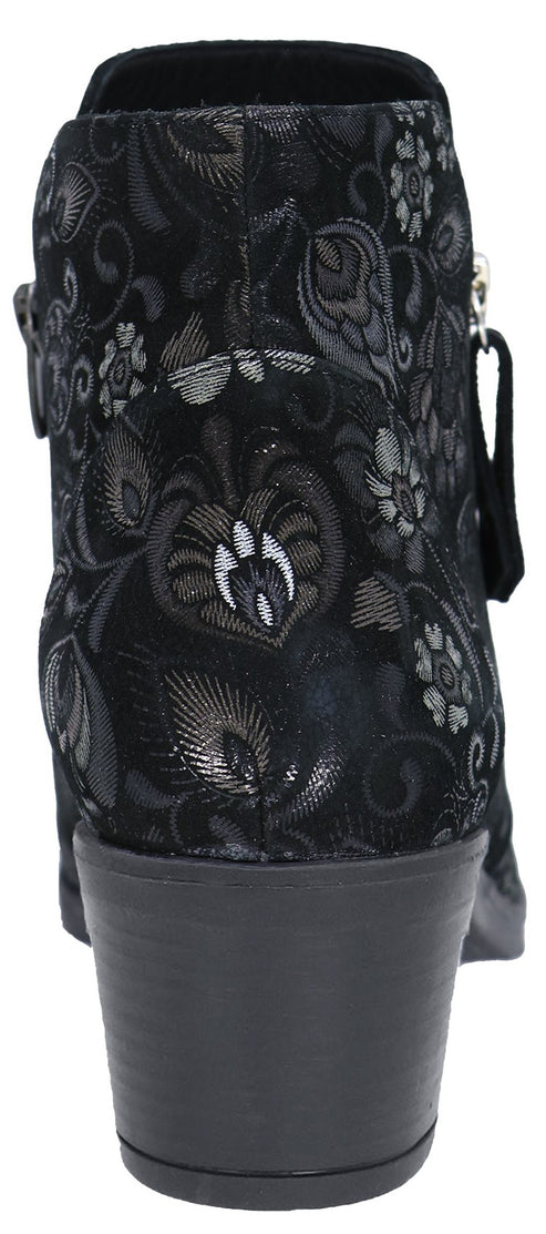 Rear view of a black ankle boot featuring an intricate, shimmering silver floral and paisley pattern, a solid black low block heel, and a side zipper pull.