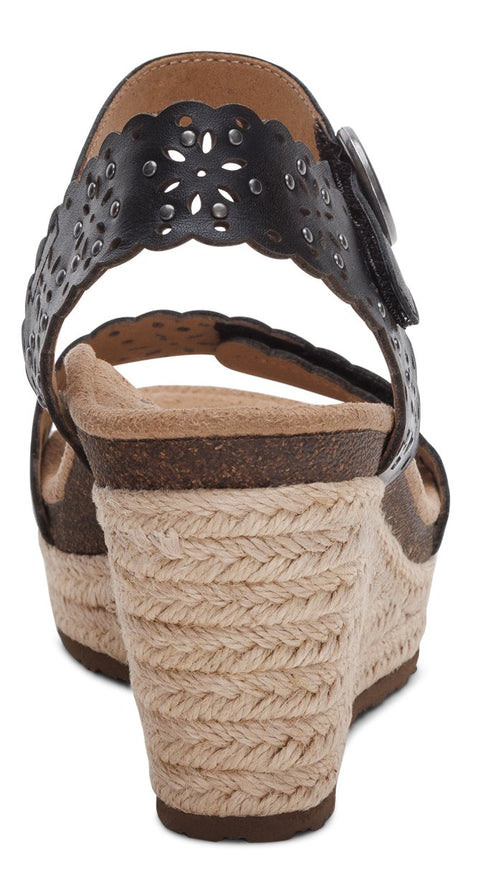 Back view of a black wedge sandal with an espadrille heel, decorative buckle, and patterned strap.