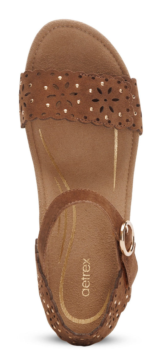 A brown sandal with decorative cutouts and a buckle.