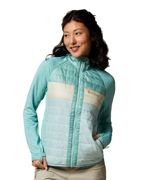A woman wearing a light blue and cream-colored, quilted jacket with long sleeves.