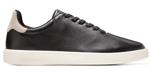 A black leather sneaker with black laces and a beige heel counter sitting on a white rubber sole.