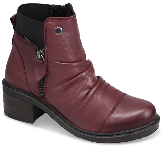 A maroon ankle boot with a rounded toe, a ruched upper, a side zipper with a small pull tab, a decorative metal button near the top, and a stacked block heel.