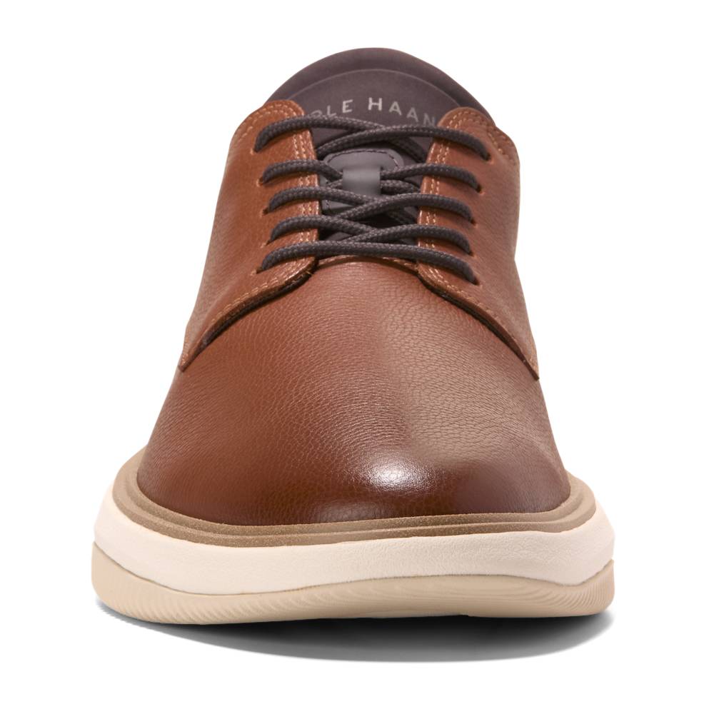 Close-up of a brown leather sneaker with dark laces and a thick, cream-colored sole.