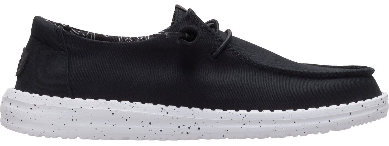 A black loafer-style shoe with a white sole speckled with black.
