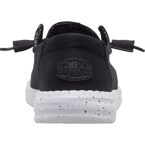 Black casual slip-on shoe with white speckled sole, displaying the text "HE DUDE".