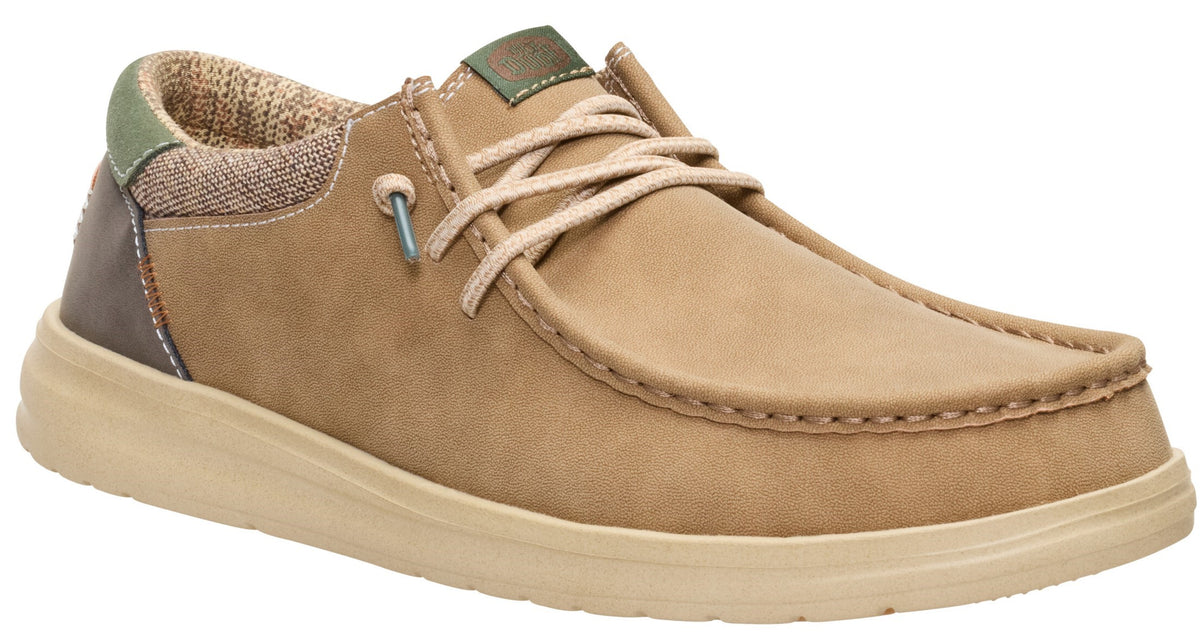 A tan slip-on shoe with a moccasin-style stitched toe, beige laces, a green heel accent, and a brown back panel, set on a thick, light-colored sole.