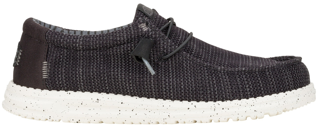 A charcoal-grey slip-on shoe with a white speckled sole.