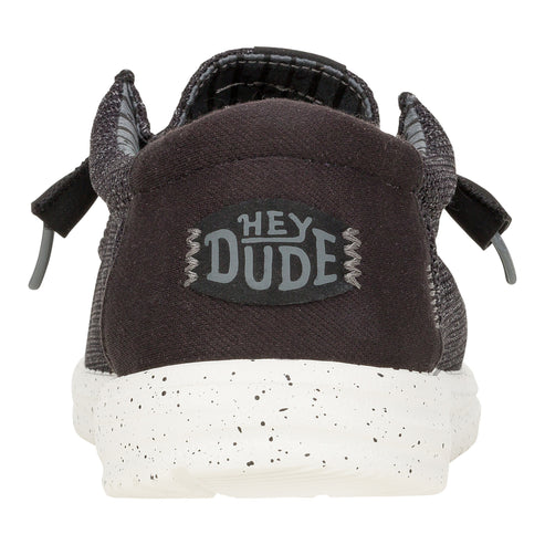 Back view of a slip-on shoe with a textured upper, gray heel with "HEY DUDE" logo, and a speckled white sole.