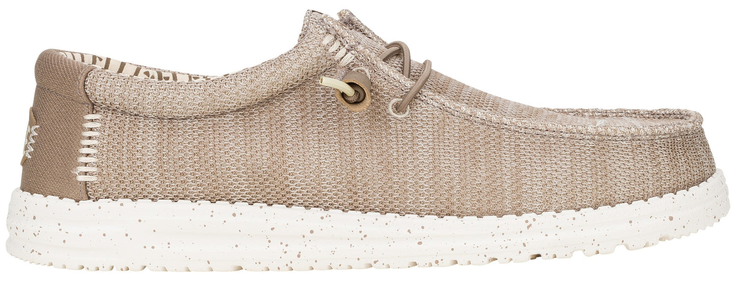 A tan slip-on shoe with a textured fabric upper, elasticized laces, a white speckled rubber sole, and stitched details at the heel.