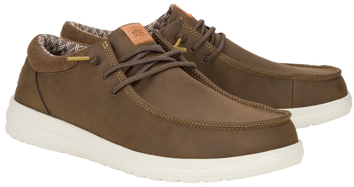 A pair of brown leather-style casual lace-up shoes with a white rubber sole, featuring a tan tongue patch and patterned lining on a plain white background.
