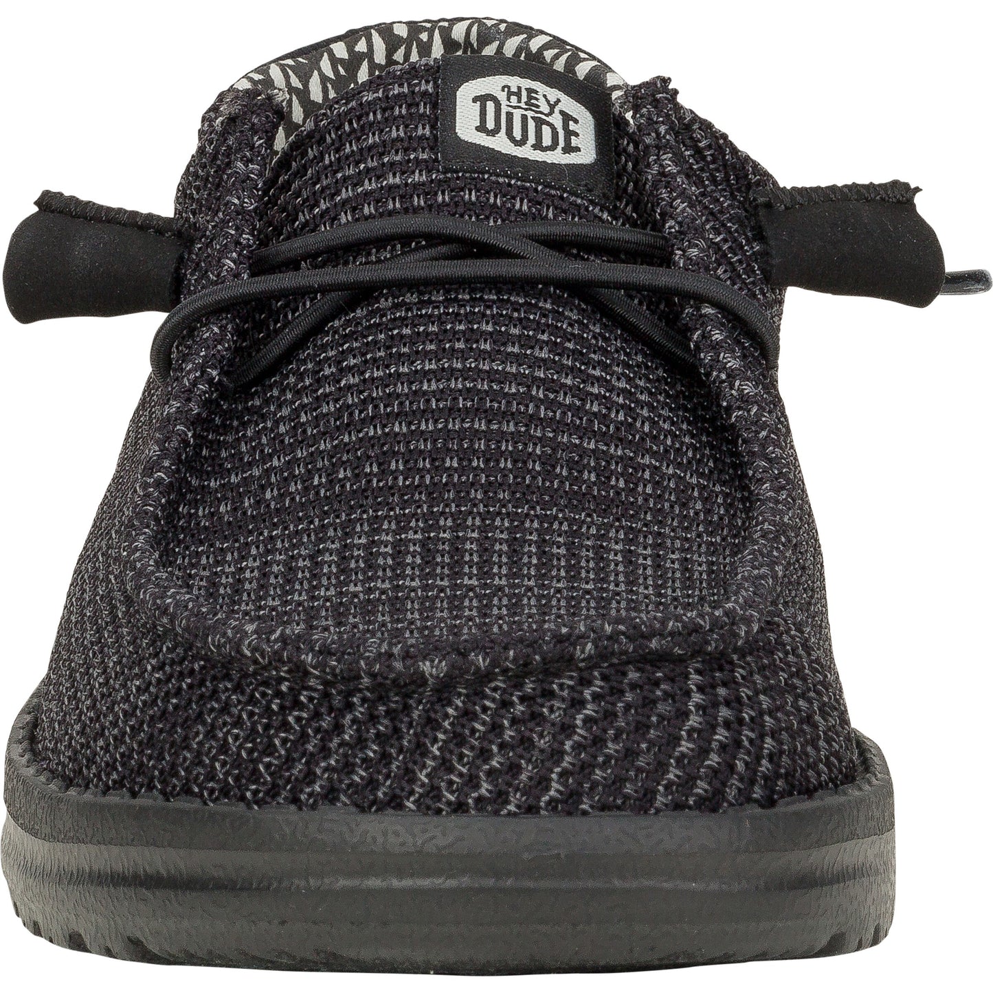 Black slip-on shoe with faux laces and a label that reads, "HEY DUDE".
