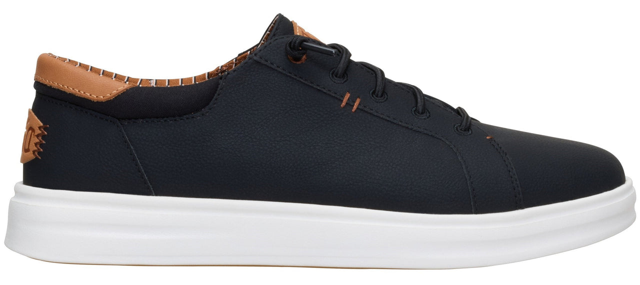 A low-profile black sneaker with tan accents on the heel and a thick white sole.