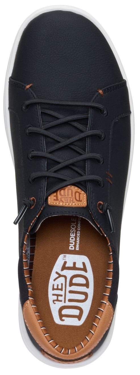 A slip-on sneaker in dark leather with laces and white soles.