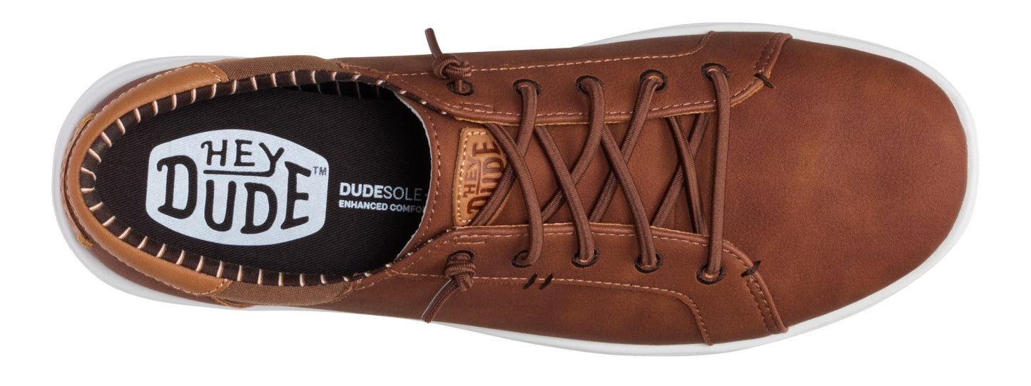 A top-down view of a laced brown shoe with a white rubber sole and the brand "Hey Dude" visible on the insole.