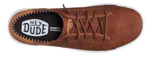 A top-down view of a laced brown shoe with a white rubber sole and the brand "Hey Dude" visible on the insole.