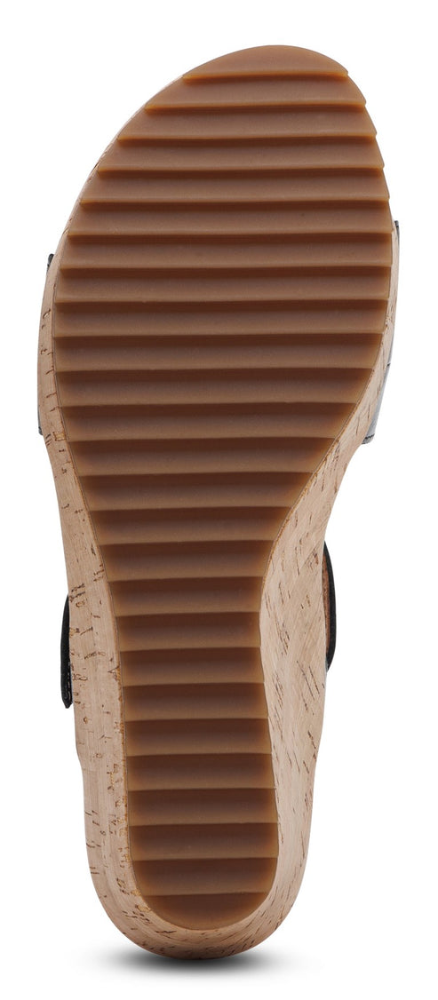 Bottom view of a wedge sandal with brown ridged soles.