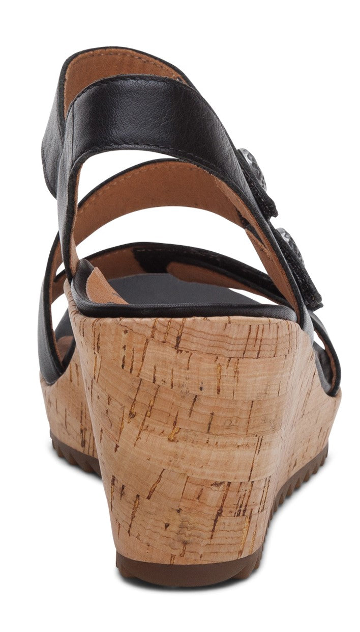 Back view of a black sandal with a cork wedge heel and two buckles.