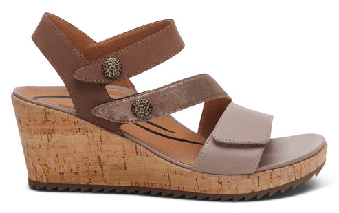 Wedge-heeled sandal with cork sole and three adjustable straps in tan, beige, and metallic accents.