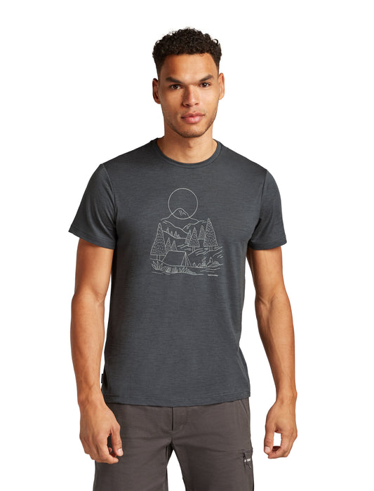 A man is wearing a dark gray t-shirt with a line art print featuring mountains, trees, and a tent.