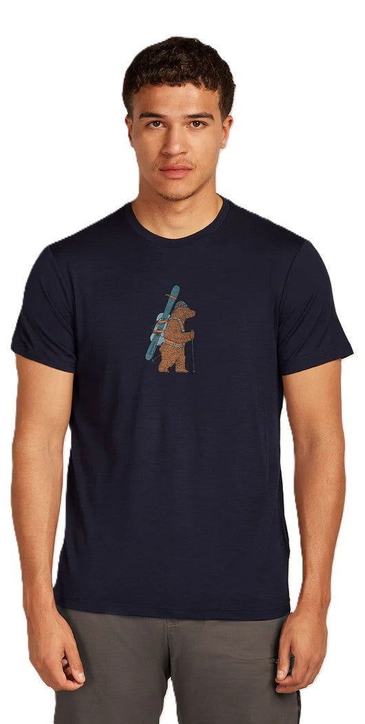 A man wearing a navy shirt with a picture of a bear holding skis.