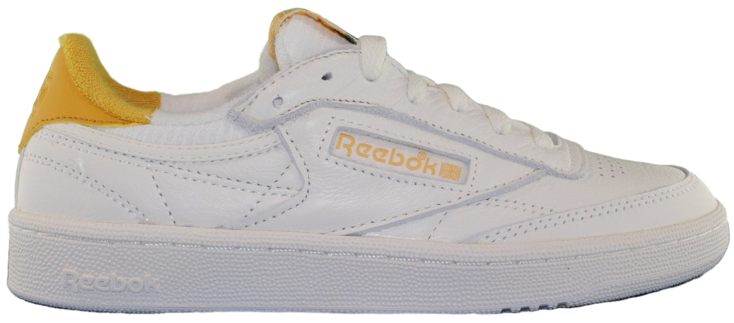 A white sneaker with a yellow accent on the heel and the Reebok logo.