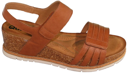 Tan leather sandal with hook and loop straps and a cork wedge heel.