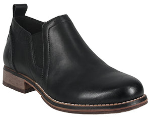 A black leather slip-on ankle boot with a low, wood-grain stacked heel, side elastic gore panels, a rounded toe, and visible stitching along the sole.