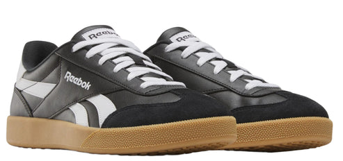 A pair of black and white sneakers with tan soles and the word "Reebok" on the side.