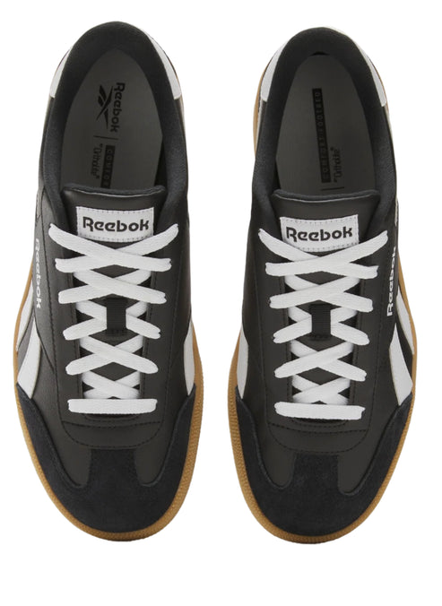 Overhead shot of black sneakers with white laces and logo, and brown soles.