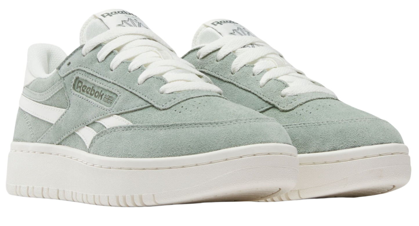 Low-top sneakers are light green suede with white laces, white side stripes, and white soles. "Reebok" is visible on the side of the shoe.