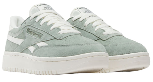 Low-top sneakers are light green suede with white laces, white side stripes, and white soles. "Reebok" is visible on the side of the shoe.
